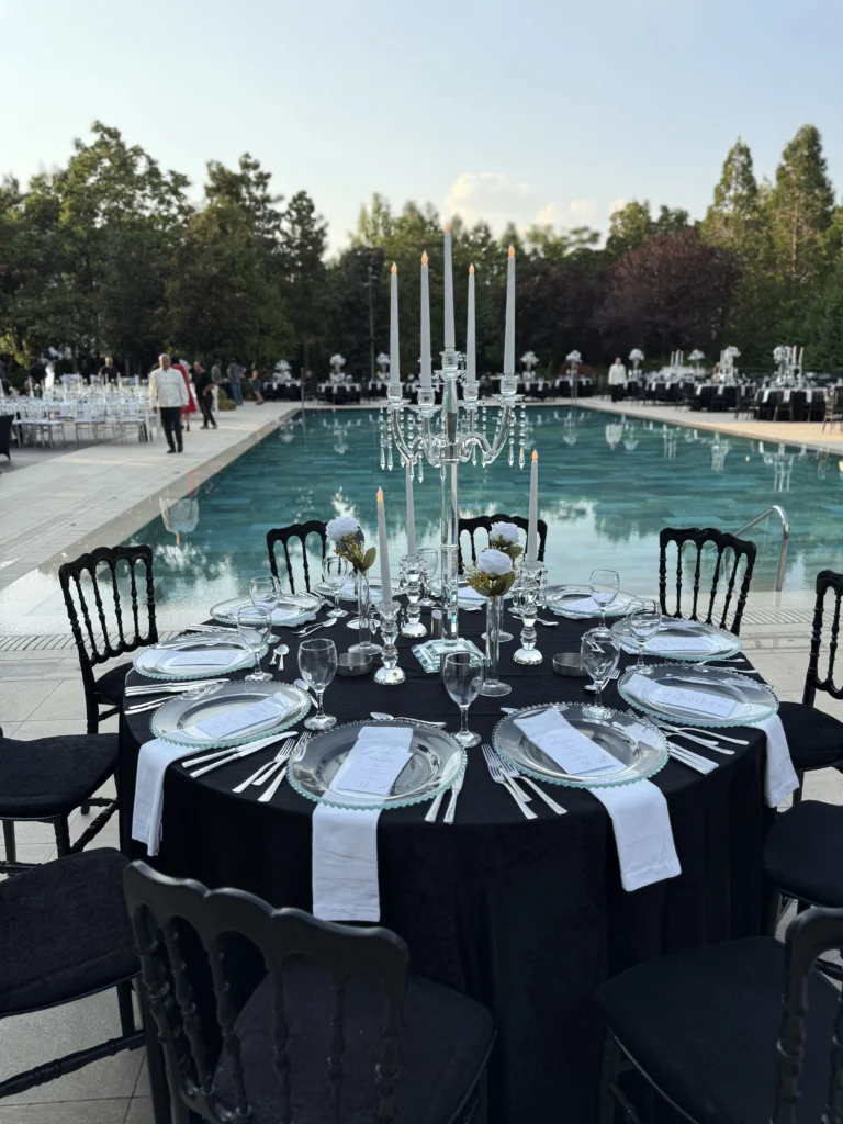 Lüks düğün organizasyonu için hazırlanan siyah örtülü masalar, kristal şamdanlar ve canlı çiçekli masa süslemesi.